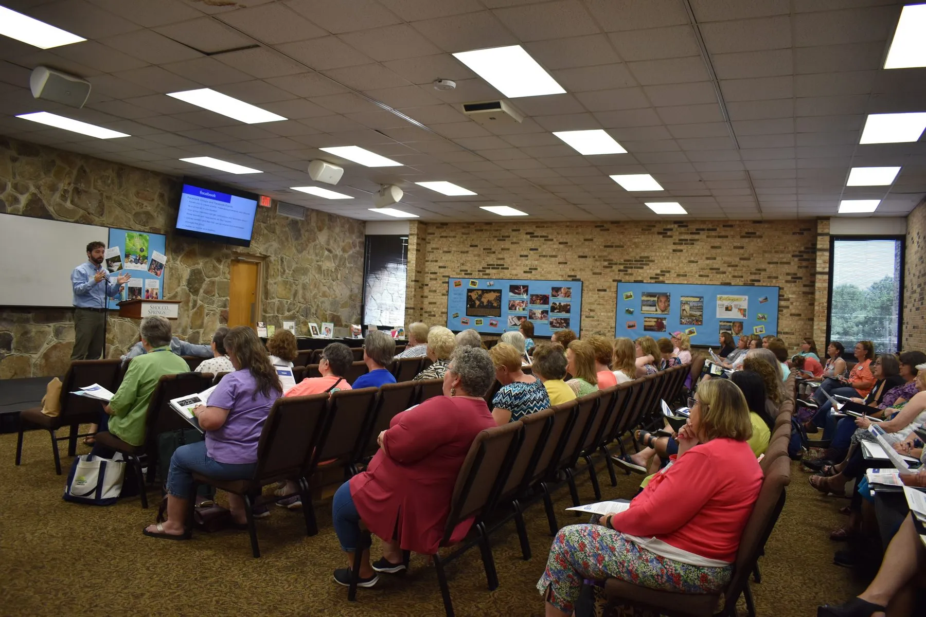 An audience seated in a meeting room during a presentation.