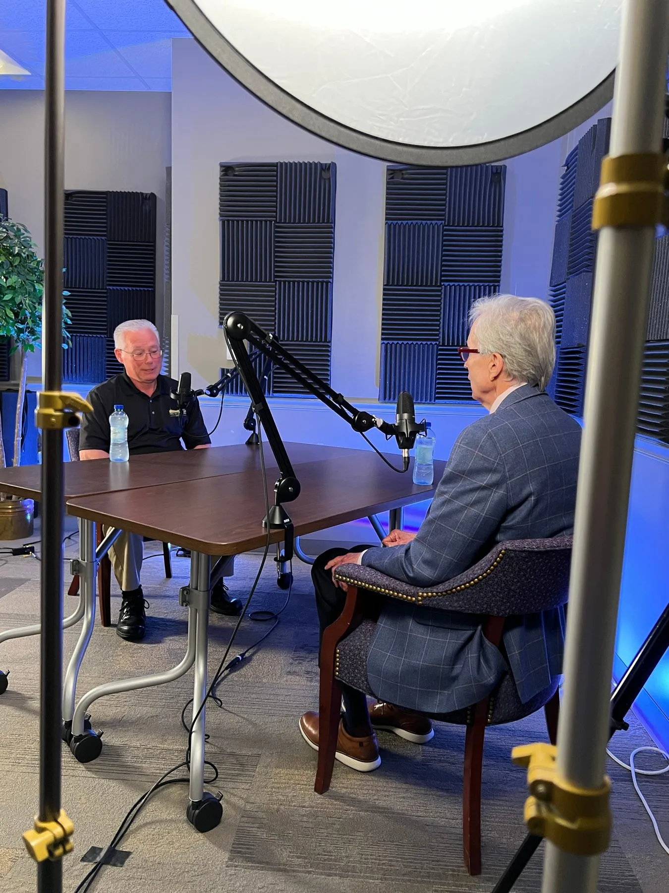 Two men recording a podcast interview in a studio with microphones and lights.